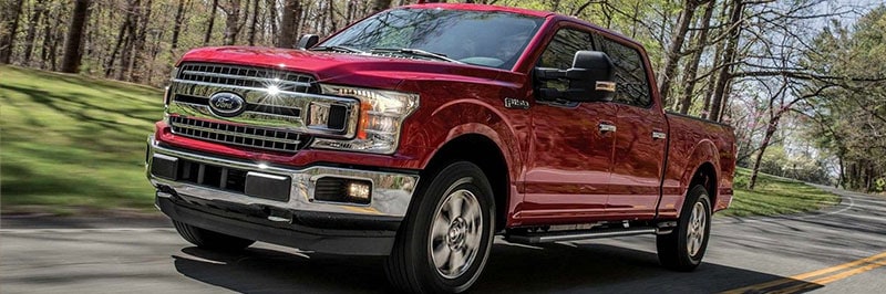 Red truck driving though forested road